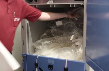 man in red shirt putting plastic in blue baler