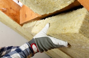 Gloved hands installing loft insulation