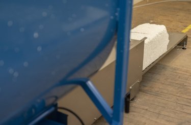 recycled polystyrene coming out in block from a blue compactor