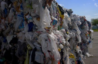 Compressed plastic waste tightly bound into large rectangular bales after being processed through a baler