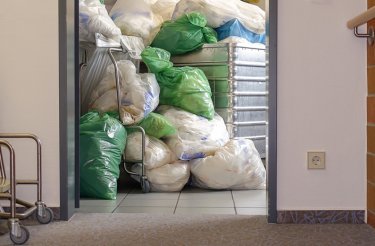 piled waste in green and clear bags in nursing home